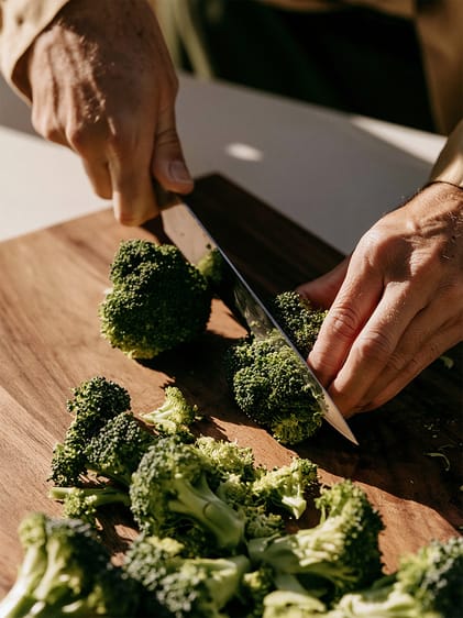 Broccoli wird auf einem Holzbrett geschnitten