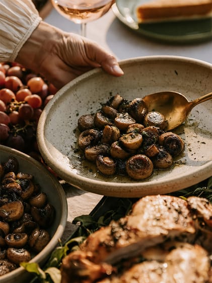 Teller mit geschmorten Champignons und Servierlöffel